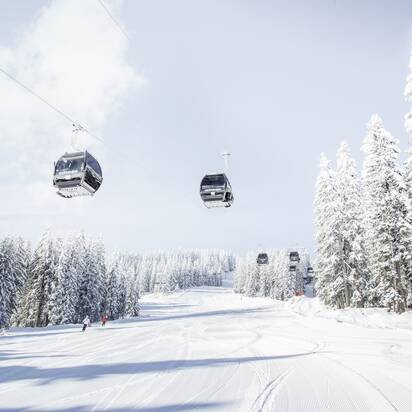 Achterjet Kabinenbahn Flachau mit Gondeln, verschneiten Tannen und präparierter Piste | © Snow Space Salzburg