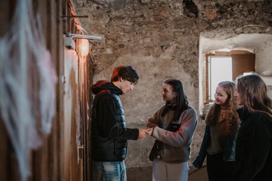 Vier Jugendliche stehen in einem alten Raum aus Stein in Radstadt und betrachten gemeinsam ein Objekt in der Hand | © Tourismusverband Radstadt/Nadia Jabli