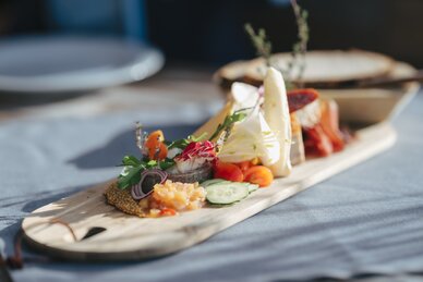 Nahaufnahme einer Jausenplatte mit Käse, Wurst, Tomaten, Gurken, Kräutern und Senfkörnern | © Ski amadé
