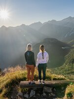 Two women enjoy the sunrise view from Graukogel overlooking Gastein Valley and the surrounding mountain peaks | © Skigastein, seven frames