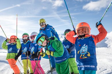 mehrere Skischulkinder mit bunten Skianzügen stehen vor dem Skilehrer auf einer Piste | © Gasteinertal Tourismus GmbH, www.felsch-foto.at