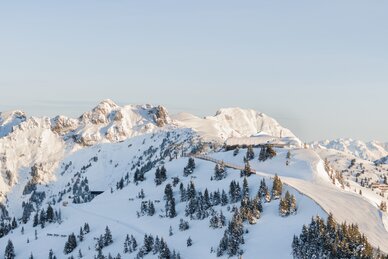 Verschneite Berge und Wälder mit präparierten Pisten, blauer Himmel und Lichtstimmung am späten Nachmittag. | © Dorfgasteiner Bergbahnen