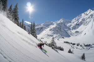 Skifahrer beim Freeriden im freien Gelände mit sonnenbestrahlten beschneiten Bergen im Hintergrund | © Gasteinertal Tourismus GmbH | Christoph Oberschneider
