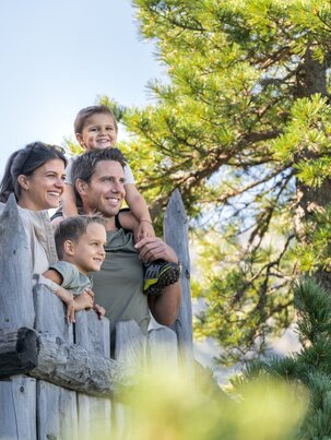 Family with two kids on wooden platform in Graukogel pine forest, looking into the distance | © Skigastein, seven frames
