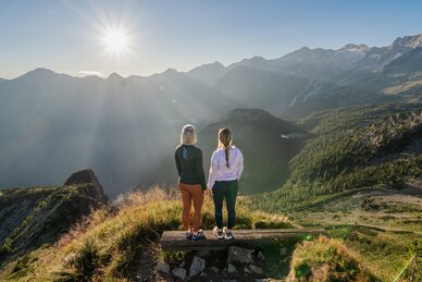 Two women enjoy the sunrise view from Graukogel overlooking Gastein Valley and the surrounding mountain peaks | © Skigastein, seven frames