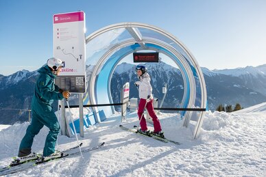 Ein Pärchen auf Skiern steht vor dem Start einer Skimovie-Strecke und unterhält sich | © Gasteiner Bergbahnen AG, Wolkersdorfer