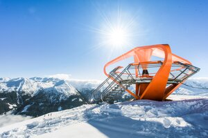 Orange Aussichtsplattform ist von Schnee umgeben und im Hintergrund ist ein schneebedecktes Bergpanorama | © Gasteiner Bergbahnen AG, Wolkersdorfer