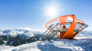Orange Aussichtsplattform ist von Schnee umgeben und im Hintergrund ist ein schneebedecktes Bergpanorama | © Gasteiner Bergbahnen AG, Wolkersdorfer