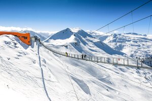 Hängebrücke spannt sich über einen Abgrund und an einem Ende ist eine orange Bergstation einer Kabinenbahn | © Gasteiner Bergbahnen AG, Wolkersdorfer