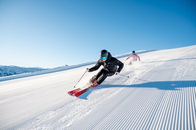 Zwei Skifahrer auf perfekt präparierten Pisten in strahlendem Sonnenschein in der Skiregion Hochkönig bei Maria Alm – Winterspaß und Naturerlebnis pur.  | © Hochkönig Tourismus GmbH