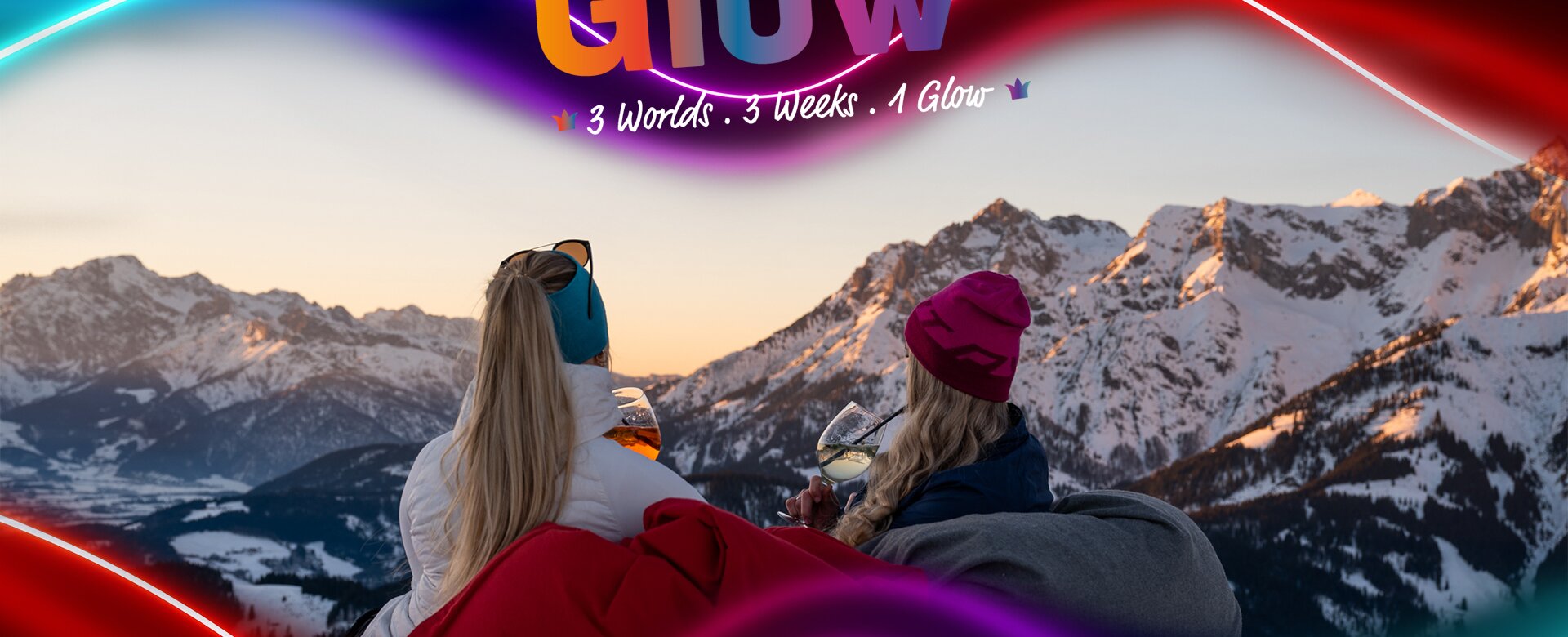Zwei Frauen sitzen mit Getränken vor verschneiten Alpen bei Sonnenuntergang, March Glow Grafik darüber
