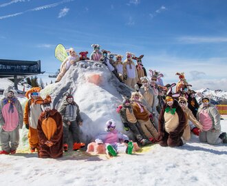Gruppe verkleideter Skifahrer als Osterhasen posiert auf Schneehügel bei Sonnenschein im Skigebiet | © Shuttleberg