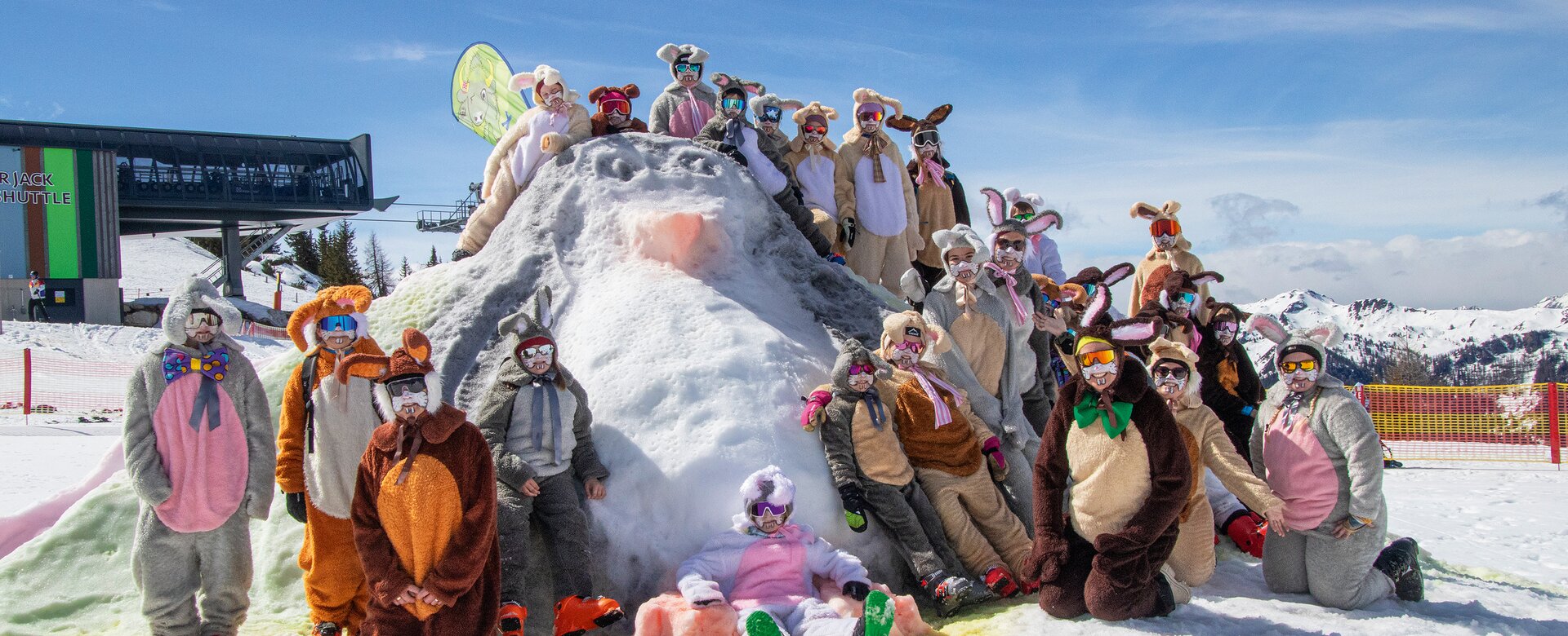 Gruppe verkleideter Skifahrer als Osterhasen posiert auf Schneehügel bei Sonnenschein im Skigebiet | © Shuttleberg