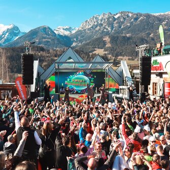 Sänger DJ Ötzi steht auf der Bühne und singt während die Menge vor der Bühne mit gehobenen Armen mitsingt. | © Hauser Kaibling