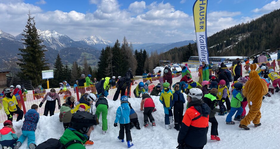 Kinder suchen im Schnee nach Ostereiern bei der Schatzsuche am Hauser Kaibling mit Blick auf verschneite Berge | © Hauser Kaibling