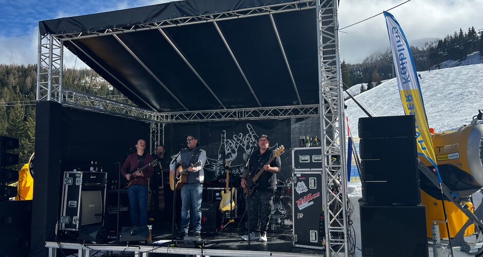 Vier Personen stehen auf einer kleinen Bühne und im Hintergrund ist eine Skipiste zu sehen  | © Hauser Kaibling