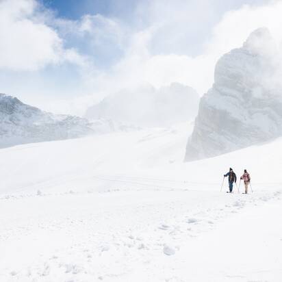 Zwei Skitourengeher gehen nebeneinander durch verschneite Berglandschaft mit Felsen | © Harald Steiner