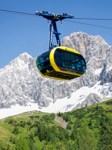 Gelbe Panorama-Gondel am Dachstein vor schneebedecktem Gletscher und steiler Felswand