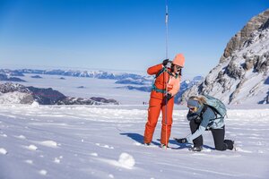Two women practice avalanche rescue with probe and transceiver in glacier snow. | © René Eduard Perhab