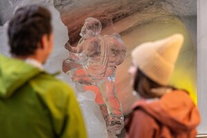 Zwei Personen betrachten eine Eisskulptur eines Kletterers im Eispalast Dachstein. | © Harald Steiner
