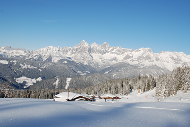 Verschneite Berghütten und Alpenpanorama mit tief verschneiten Bäumen auf der Fageralm.