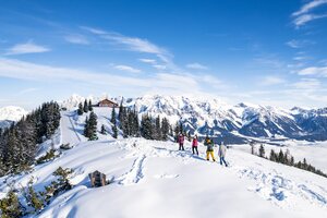 Winterwanderer vor schneebedeckten Bergen und blauem Himmel im Hintergrund. | © Gerald Oberreiter