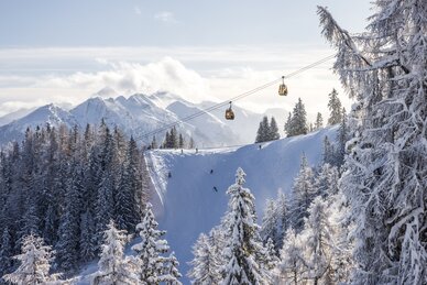 Schneeweiße Landschaft mit Skifahrern, Gondeln und Bergen im Hintergrund. | © Martin Huber