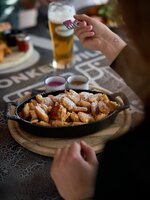 Frisch gebackener Kaiserschmarrn mit Staubzucker in Pfanne, dazu drei Saucen und Bierglas auf Hüttentisch der Planai. | © Dietmar Körbler