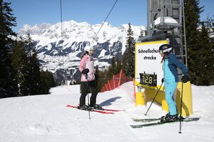 Zwei Skifahrerinnen an der Schnellschussstrecke auf der Planai, eine schaut auf die digitale Geschwindigkeitsanzeige von 72,8 km/h. | © Herbert Raffalt