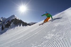 Skifahrer mit grünem Helm fährt carving auf frisch präparierter Planai-Piste. | © Gregor Hartl