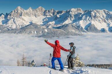 Zwei Skifahrer stehen auf der Reiteralm, blicken auf Nebelmeer und verschneite Berge. | © Lorenz Masser