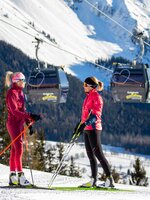 Two women in cross-country skiing gear talk to each other.