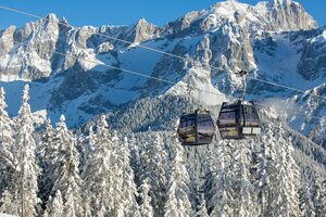 Two cabins of the Rittisberg combination lift with snowy mountains.
