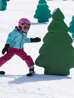Kind fährt auf Skiern um ein Hindernis in der Form eines Baumes herum