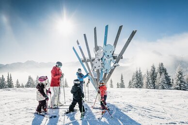 Kinder mit Begleitperson auf Skiern vor Holzskulptur mit Tierfiguren am Family Run im Shuttleberg | © Shuttleberg