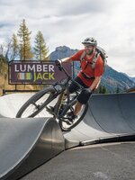 A mountain biker rides over a wave on the paved pump track in front of the Lumberjack. | © Shuttleberg