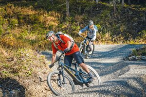 Two mountain bikers cornering on a gravel pump trail with strong lean angles. | © Shuttleberg