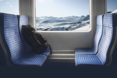 Vier Zugplätze und im Fenster ist eine verschneite Winterlandschaft zu sehen