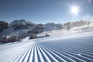 Perfekt präparierte Skipisten im Skigebiet Alpendorf mit Sonne, Schnee und Bergen