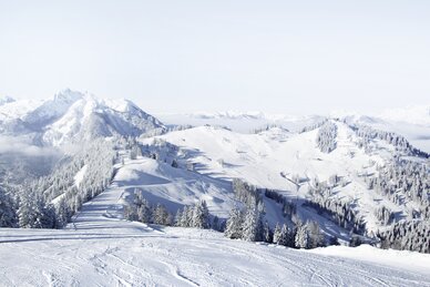 Schneereiche Pistenlandschaft mit Blick auf die umliegenden schneebedeckten Berge mit strahlend blauem Himmel | © Snow Space Salzburg