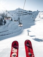 Skigebiet St. Johann – Alpendorf mit Sessellift, verschneiten Pisten, Skifahrern und Bergen