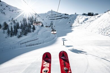Skigebiet St. Johann – Alpendorf mit Sessellift, verschneiten Pisten, Skifahrern und Bergen