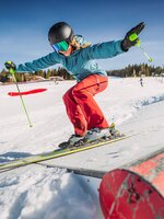 Ein Mädchen fährt mit ihren Skier über ein Action Hindernis.