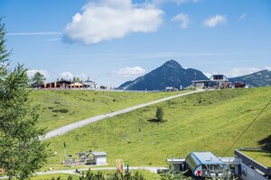 Blick auf Gamskogelbahn-Bergstation, Panoramaweg, Almhütte und Berglandschaft in Zauchensee bei klarem Sommerwetter. | © Matthias Fritzenwallner