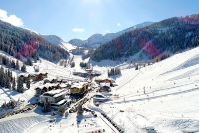 Zauchensee Talstation mit Pisten, Liften und verschneiten Bergen, Skifahrer genießen die Sonne