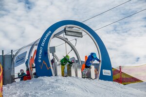 Zwei junge Skifahrer starten gleichzeitig aus dem Skimovie-Tor in Zauchensee