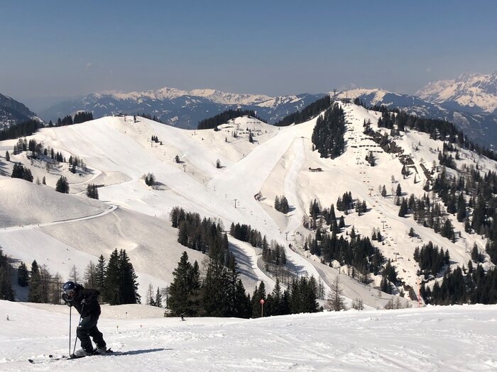Panoramic view over sunny ski slopes in Ski amadé | © Anna Pilz Skier enjoys the view of snow-covered mountains and slopes. | © Anna Pilz