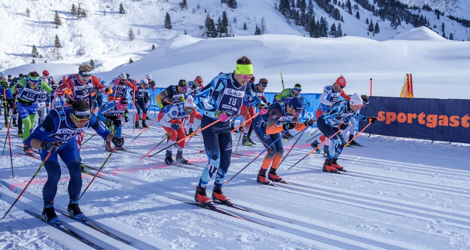 Start des Männerrennens bei den Gastein Classics im Sonnenschein | © Gasteinertal Tourismus, Christoph Oberschneider Zahlreiche männliche Langläufer starten dynamisch nebeneinander im Sonnenschein auf der Loipe. | © Gasteinertal Tourismus, Christoph Oberschneider