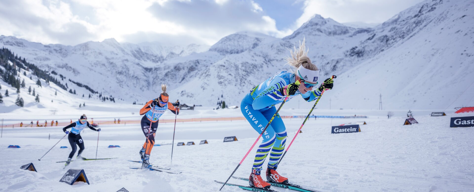 Three female skiers racing in Gastein through a snowy alpine landscape with mountains behind | © Gasteinertal Tourismus, Christoph Oberschneider