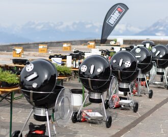 Grillstationen für das Wintergrillen auf der Planai | © Harald Steiner Reihe schwarzer Kugelgrills mit Zubehör auf einer Terrasse mit Blick auf Bergpanorama. | © Harald Steiner